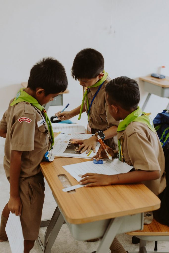 school boys in uniforms studying by desks
